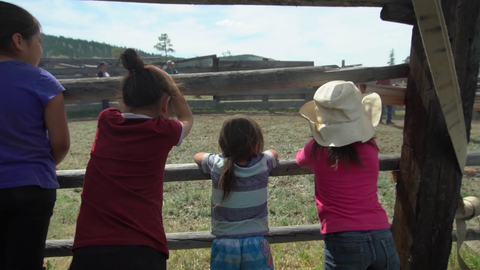 Children watching from the corral fence at a community gathering